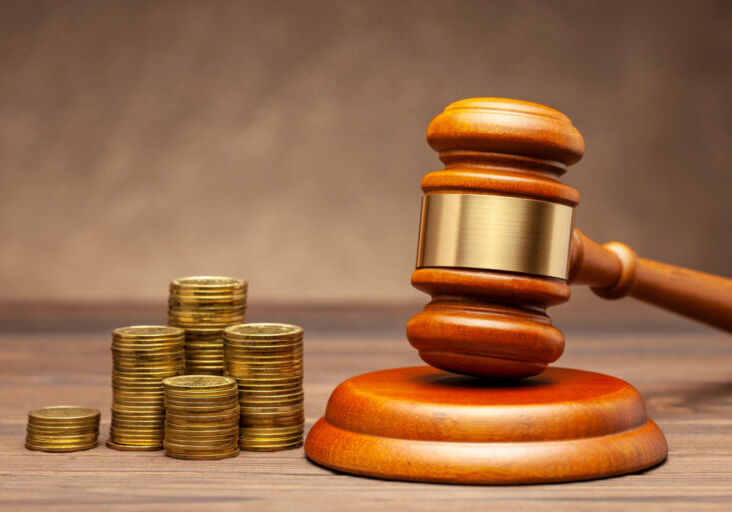 Stack of coins and judge gavel on brown background. The concept of non-payment of taxes