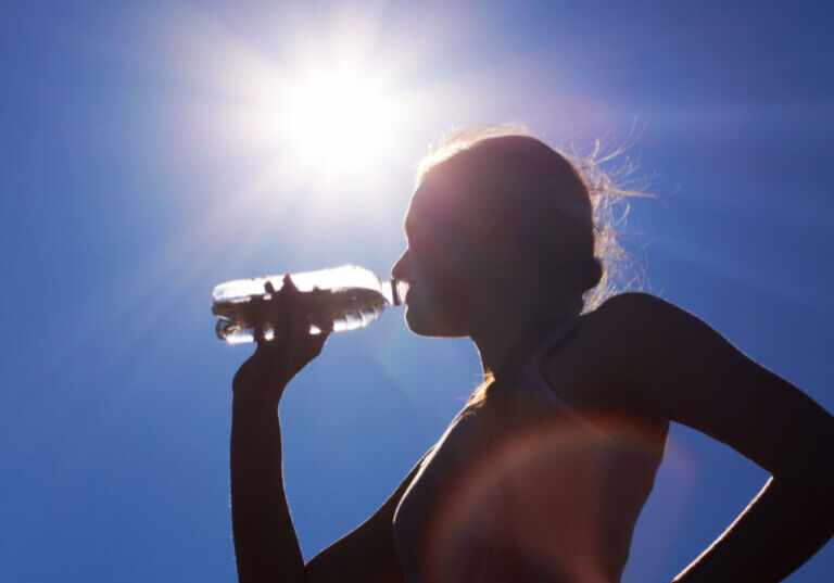 Rehydrating under the sun. Low angle silhouette shot of a woman Rehydrating under the sun. Low angle silhouette shot of a woman