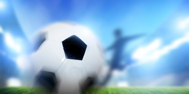 Football, soccer match. A player shooting ball on goal